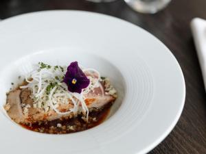 a white plate with a bowl of food on a table at Les Boréales - Appart'hotel & Restaurant in Rouen
