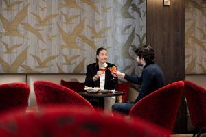 two women sitting at a table with wine glasses at Les Boréales - Appart'hotel & Restaurant in Rouen