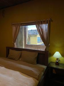 a bedroom with a bed with a window and a lamp at LoLo Hideaeay in Dồng Văn