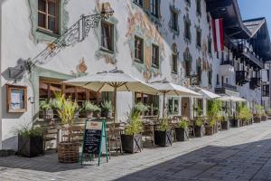 a street with tables and umbrellas in front of a building at Hotel Wirtshaus Post in Sankt Johann in Tirol