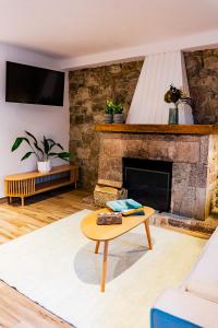 a living room with a stone fireplace and a coffee table at Apartamentos y Pensión El Campanu in Cangas de Onís