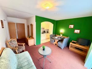 a living room with green walls and a couch and a table at Apartment House Seerose self check-in in Obertraun