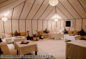 a tent with tables and couches in a room at Sahara Luxurious Tented in Merzouga