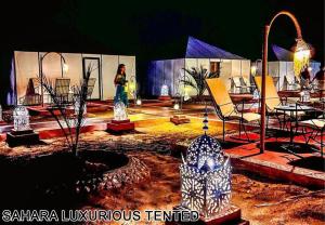 a woman standing in a courtyard with a lot of vases at Sahara Luxurious Tented in Merzouga