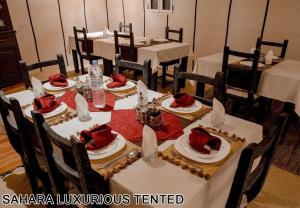 a dining room with tables and chairs with red food on them at Sahara Luxurious Tented in Merzouga