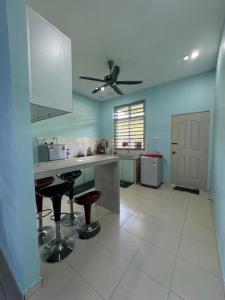a kitchen with two bar stools and a ceiling fan at De Chempedak Homestay in Kampong Jarak +8 photos