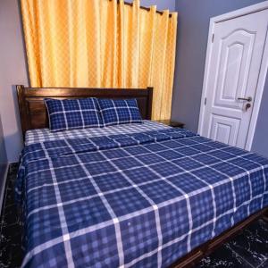 a bed with a blue and white checkered blanket at Rapid City in Oshiyie