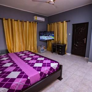 a bedroom with a purple bed and a tv at Rapid City in Oshiyie