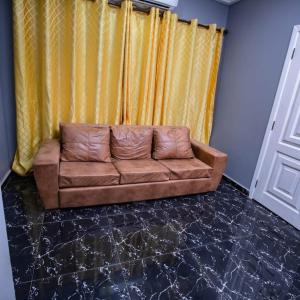 a brown couch in a living room with yellow curtains at Rapid City in Oshiyie