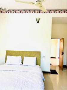 a bedroom with a large white bed with a ceiling fan at Lotus hotel in Nāthdwāra