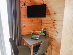ein Tisch mit Stuhl und ein Fernseher an der Wand in der Unterkunft Keith in Stranraer