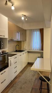 a kitchen with white cabinets and a sink and a table at ZBI Apartament in Oradea +6 photos