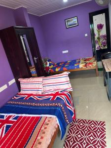 a bedroom with two beds and a purple wall at Matha Tourist Home , Cherupuzha in Peringom
