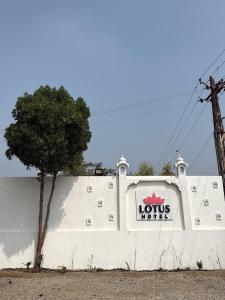 a white wall with a sign on it with a tree at Lotus hotel in Nāthdwāra +2 photos