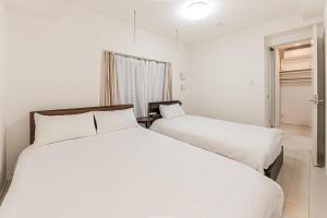 two beds in a hotel room with white sheets at japan house Otsuka in Tokyo