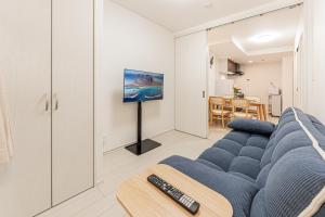 a living room with a blue couch and a tv at japan house Otsuka in Tokyo