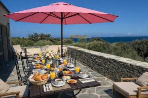 a table with food and an umbrella on a patio at Villa MARINE in Ersa