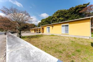 a yellow building with a sidewalk next to a yard at Shimabara 結 Terrace in Shimabara