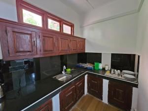 a kitchen with wooden cabinets and a black counter top at Alpha bungalow in Kandy