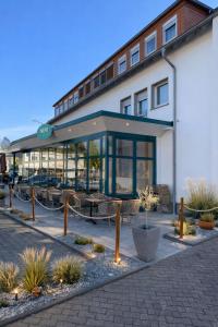 a building with tables and chairs in front of it at Hotel Klusenhof in Lippstadt