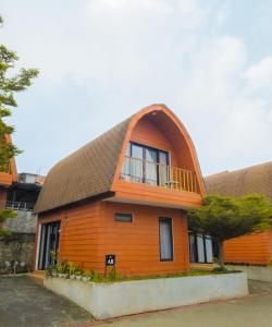 a large wooden house with a gambrel roof at Pakuhaji Highland Ecoresort in Panjadakan