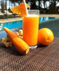 a glass of orange juice sitting on a table with oranges at Retraite soleil sérénité in Pamunugama