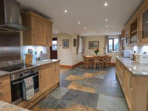 a large kitchen with wooden cabinets and a dining room at Orcaber Farm Barn in Lancaster