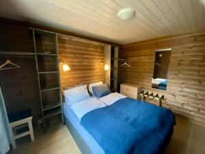 a bedroom with a blue bed and a wooden wall at Heinåli Hytta in Isfjorden