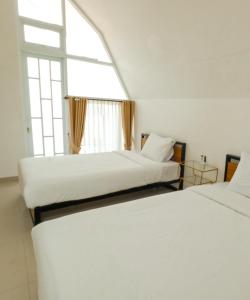 two beds in a room with a window at Pakuhaji Highland Ecoresort in Panjadakan +24 photos