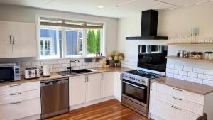 a kitchen with white cabinets and stainless steel appliances at The Black Barn At Puketitiri in Puketitiri
