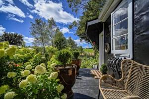 a porch with two benches and plants on a house at The Black Barn At Puketitiri in Puketitiri