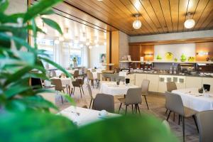 a restaurant with tables and chairs and a kitchen at Hotel Wartburg in Stuttgart