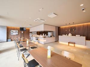 a restaurant with tables and chairs and a kitchen at Hotel ARM ObihiroEkimae in Obihiro