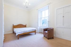 a bedroom with a bed and a chair and a window at OYO Ashlea Manor in Monifieth