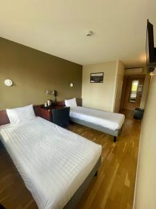 a hotel room with two beds and a desk at Hôtel Valpré in Écully