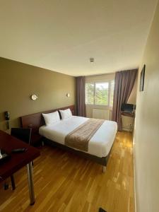 a hotel room with a large bed and a desk at Hôtel Valpré in Écully