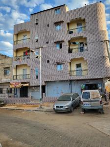 a building with two cars parked in front of it at Studio Terminus 61 in Keur Massar