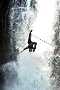a person on a rope in the middle of a waterfall at Nyoman Guest House in Singaraja