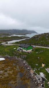 a house in a field next to a body of water at Gjesvaer Fishing in Gjesvær