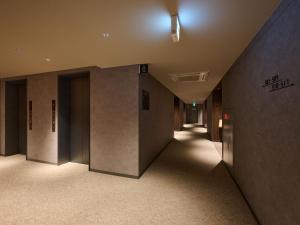 an empty hallway of a building with lights on at Hotel ARM ObihiroEkimae in Obihiro