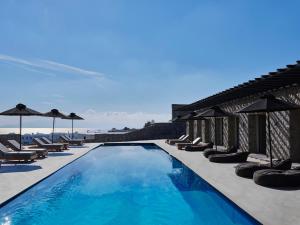 a swimming pool with chairs and umbrellas next to the ocean at Villa Christy in Psarou