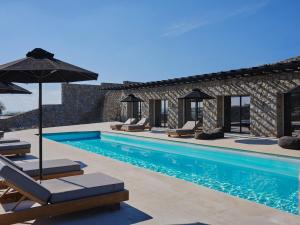 a swimming pool with lounge chairs and an umbrella at Villa Christy in Psarou