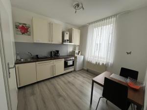a kitchen with white cabinets and a table and a window at Pension Belo Sono München in Munich