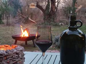a glass of red wine next to a fire pit at Baglyos Vendégház Kulcs in Kulcs