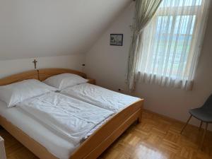a bedroom with a bed and a window and a chair at Haus am Ring in Spielberg +6 photos