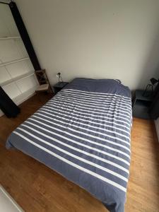 a bed with a blue and white striped blanket in a room at Côte Saint-Pierre in Ambleteuse