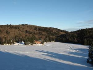 un grand champ couvert de neige devant une montagne dans l'établissement Aux Berges du lac Castor, à Saint-Paulin