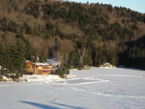 une maison sur un lac gelé en face d'une montagne dans l'établissement Aux Berges du lac Castor, à Saint-Paulin