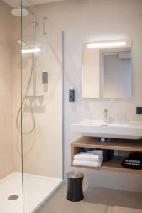 a bathroom with a shower and a sink and a mirror at Brit Hotel Saint Malo – Le Transat in Saint Malo