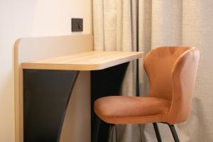 a desk with a chair next to a curtain at Brit Hotel Saint Malo – Le Transat in Saint Malo